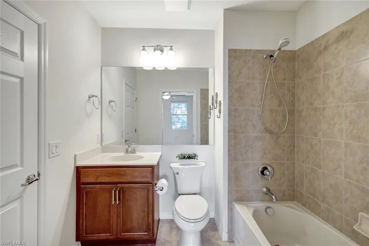 Full bathroom featuring tiled shower / bath, vanity, ceiling fan, toilet, and tile patterned floors