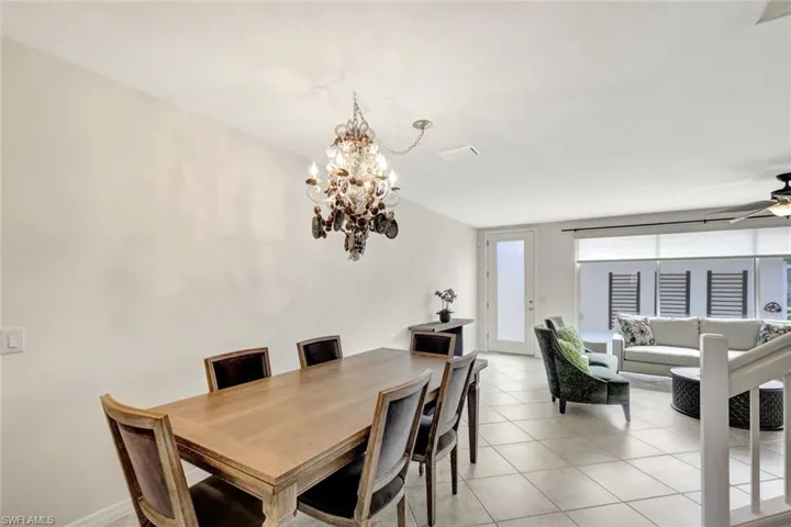 Tiled dining space featuring ceiling fan with notable chandelier