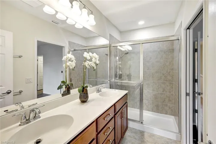 Bathroom featuring a shower with door, vanity, and tile patterned flooring