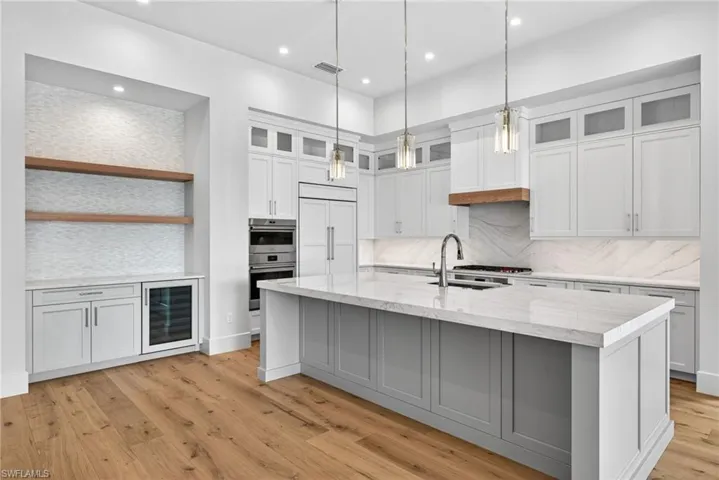 Large kitchen island , two tone cabinets wet bar and wine cooler, and simple pendant lighting
