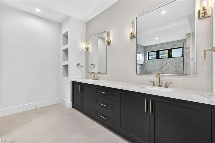 Master bathroom with double vanity, built in features, recessed lighting, and a marble finish shower