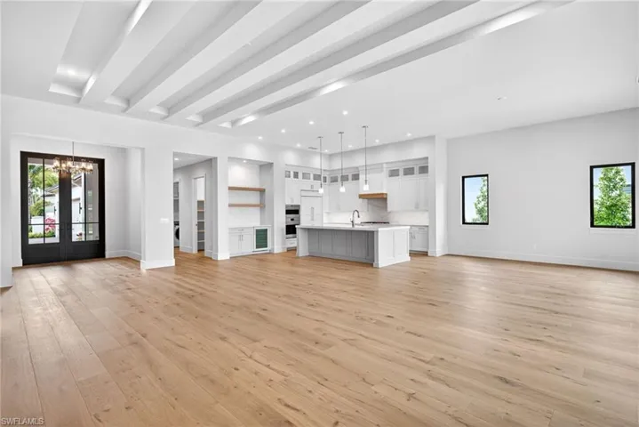 living room featuring plenty of natural light, recessed lighting, light wood flooring, 10 foot high french doors, and beam ceiling