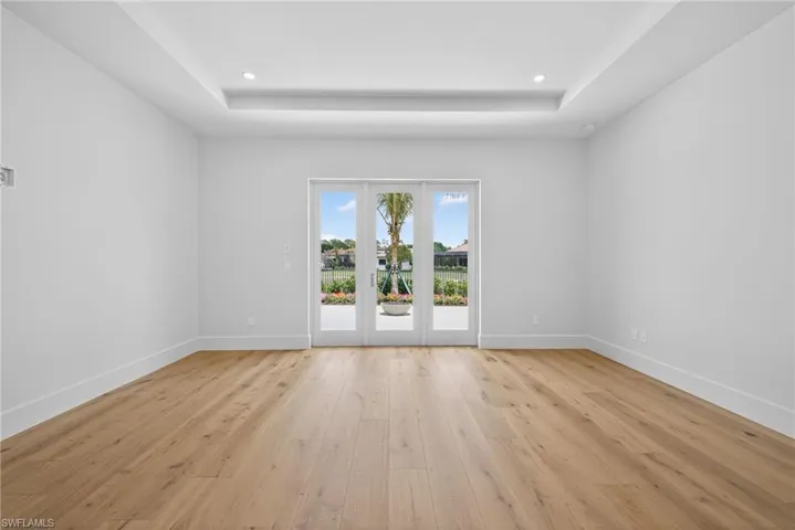 Master bedroom with lots of natural lighting, wood flooring, a tray ceiling, and recessed lighting