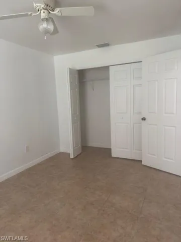 Unfurnished bedroom featuring a closet, a ceiling fan, and light tile patterned flooring