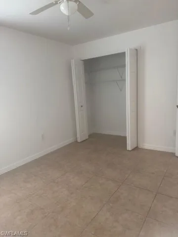 Unfurnished bedroom featuring a closet, a ceiling fan, and light tile patterned floors