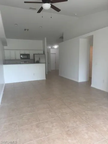 Unfurnished living room featuring ceiling fan, lofted ceiling, and light tile patterned floors