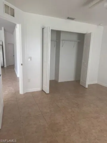 Unfurnished bedroom featuring a closet, a ceiling fan, and light tile patterned floors