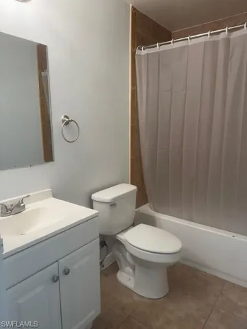 Bathroom with vanity, shower / bath combination with curtain, and tile patterned flooring