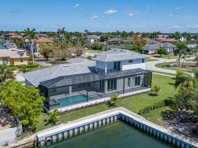 Back of property featuring a residential view, an outdoor pool, a patio area, a lawn, and glass enclosure