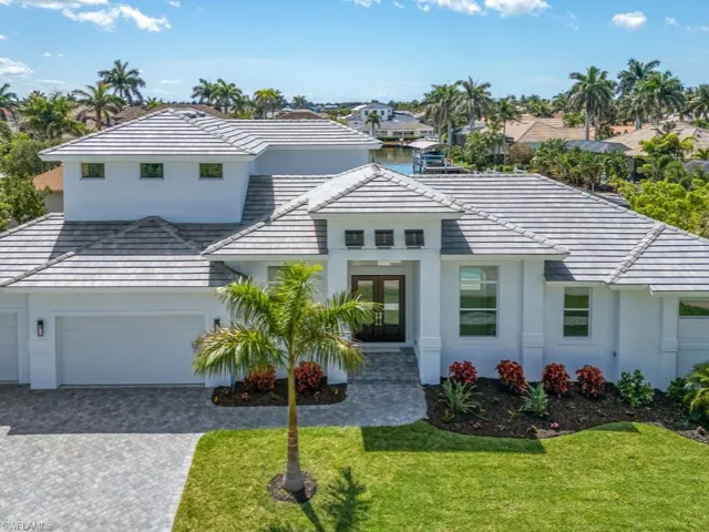 View of front of home featuring stucco siding, a front lawn, driveway, and a tile roof