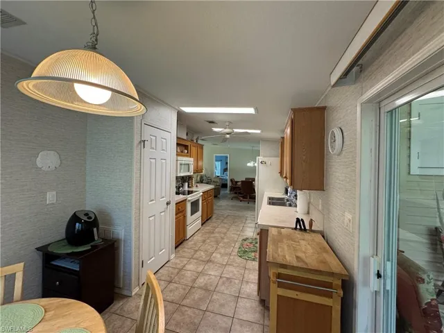 Kitchen with light tile patterned floors, white appliances, a sink, visible vents, and brown cabinets