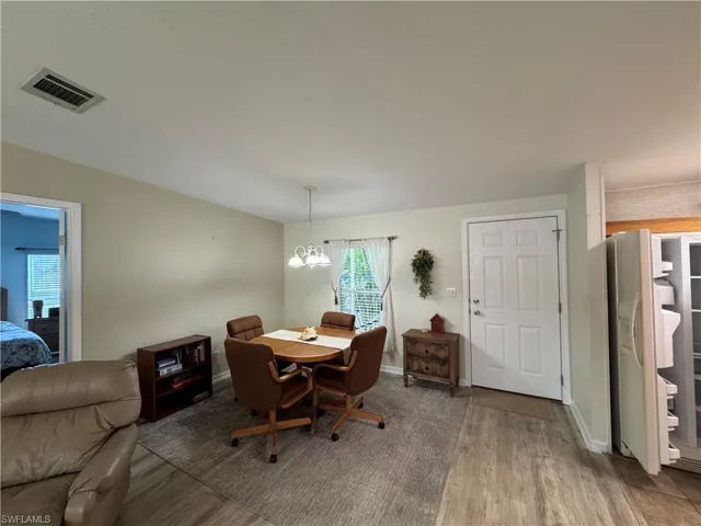 Dining area with visible vents, a notable chandelier, baseboards, and wood finished floors