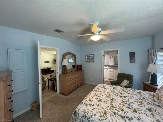 Carpeted bedroom featuring a textured ceiling, a ceiling fan, visible vents, and baseboards