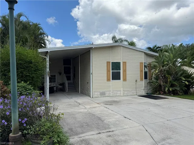 Back of house featuring entry steps, driveway, an attached carport, and crawl space
