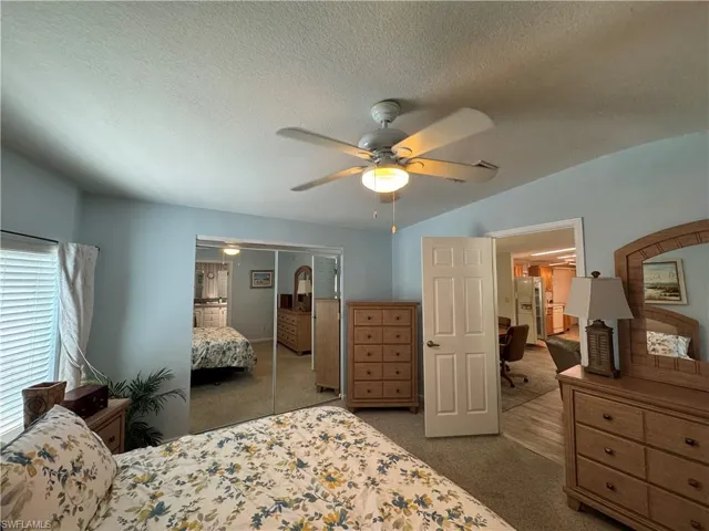 Bedroom with a textured ceiling, carpet floors, a closet, and refrigerator with ice dispenser