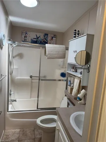 Bathroom featuring toilet, shower / bath combination with glass door, tile patterned flooring, and vanity