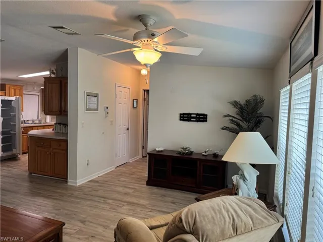 Living room featuring lofted ceiling, visible vents, light wood-style flooring, ceiling fan, and baseboards