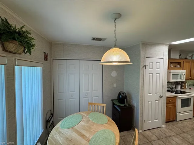 Dining room featuring light tile patterned floors, visible vents, and ornamental molding