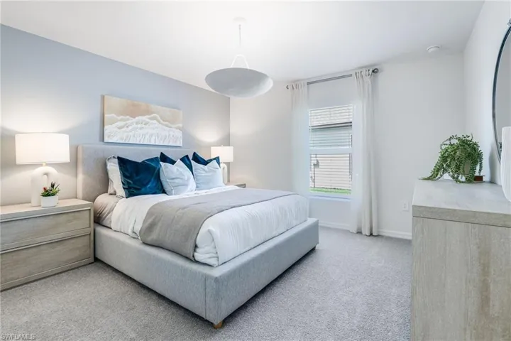 Spacious bedroom featuring light gray walls, plush carpeting, a large window with blinds, and a contemporary ceiling fixture