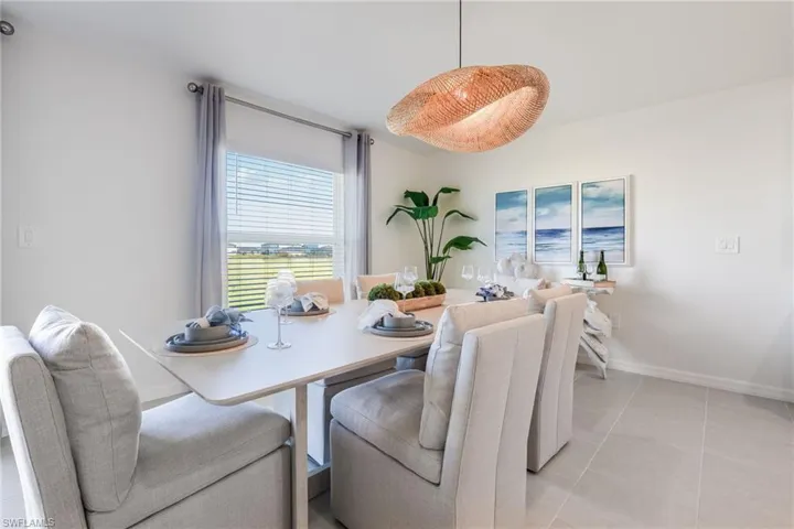 Bright dining area featuring a large window, a unique woven pendant light fixture, and light-toned floor tile