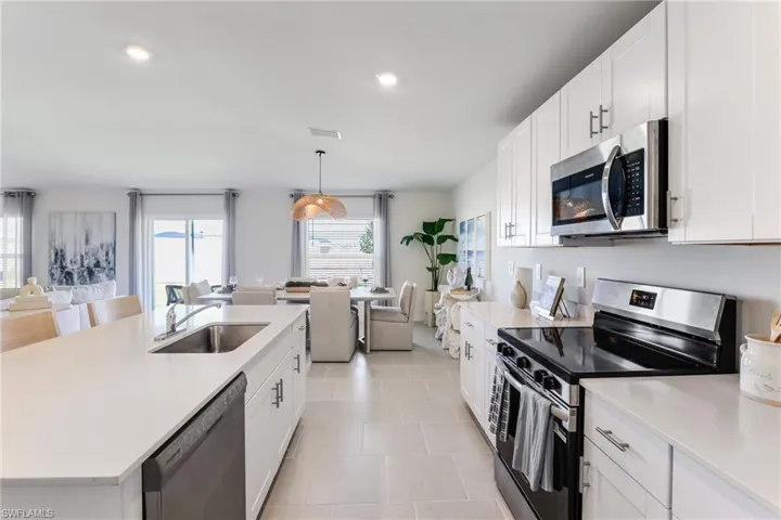 Modern kitchen featuring white cabinetry, stainless steel appliances, light-toned countertops, and recessed lighting