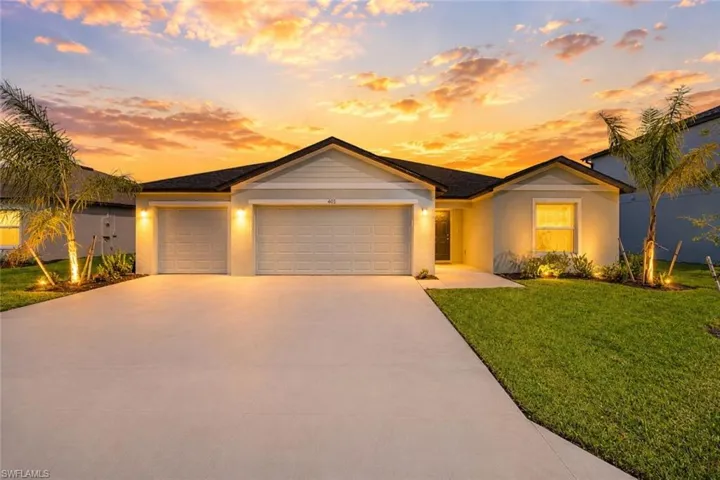 Contemporary exterior featuring a two-car garage, expansive concrete driveway, manicured lawn, and mature palm trees