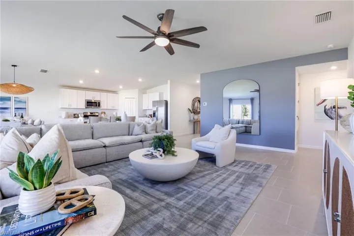 Spacious living area featuring light-toned tile flooring, recessed lighting, and a ceiling fan