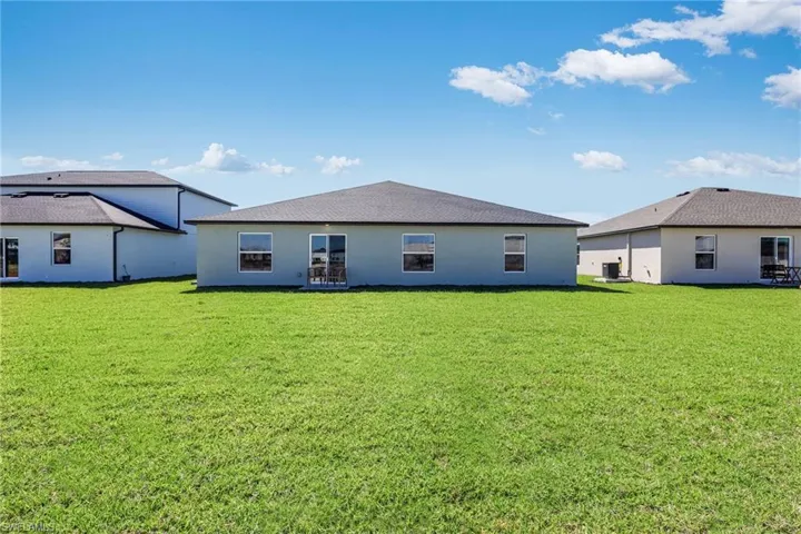 Expansive green lawn extending from a stucco exterior with multiple windows