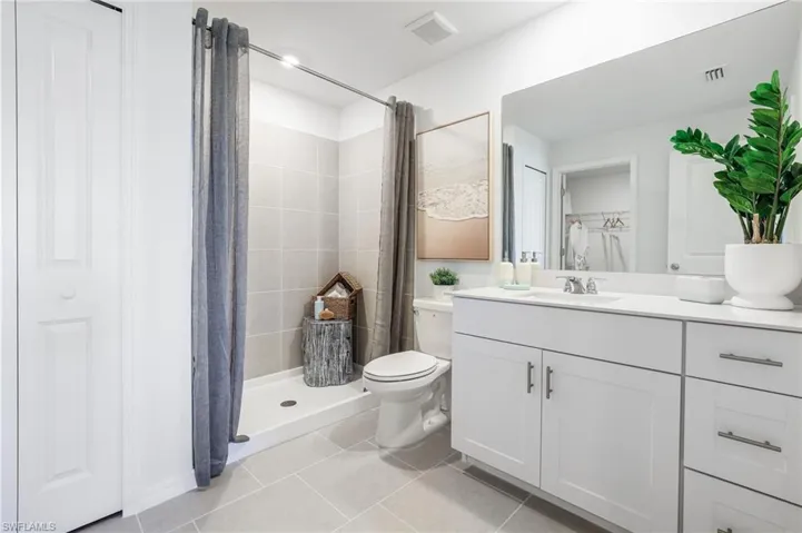 Bathroom with a single vanity featuring a white countertop and white cabinetry with brushed nickel hardware