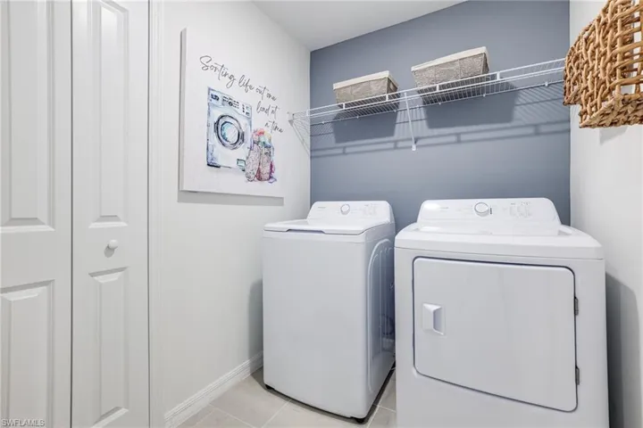 Dedicated laundry area featuring a neutral color palette, integrated wire shelving, and durable tile flooring