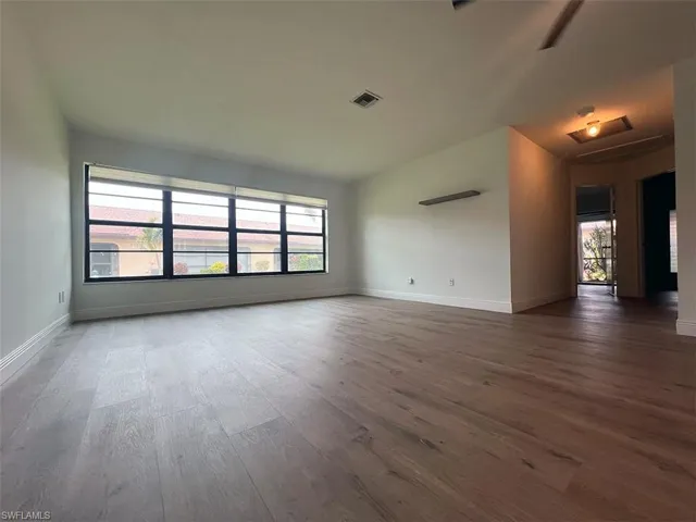 Empty room featuring dark wood-type flooring and healthy amount of natural light