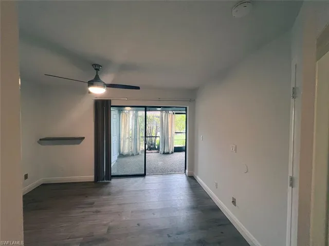 Unfurnished room featuring dark wood-style flooring and a ceiling fan