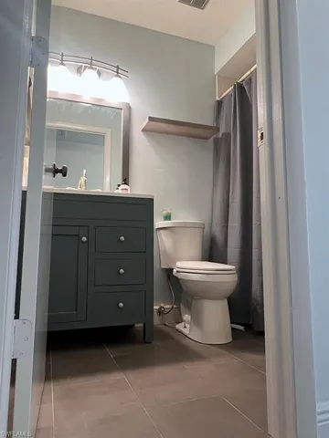 Full bathroom featuring vanity, a shower with curtain, and dark tile patterned flooring