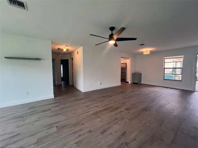 Unfurnished living room with a ceiling fan and dark wood-type flooring