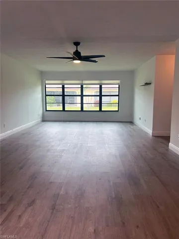 Spare room with ceiling fan, healthy amount of natural light, and dark wood-type flooring