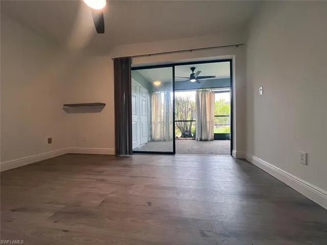 Unfurnished room with ceiling fan and dark wood-style flooring