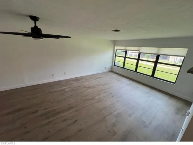Spare room featuring dark wood-type flooring, a textured ceiling, and ceiling fan