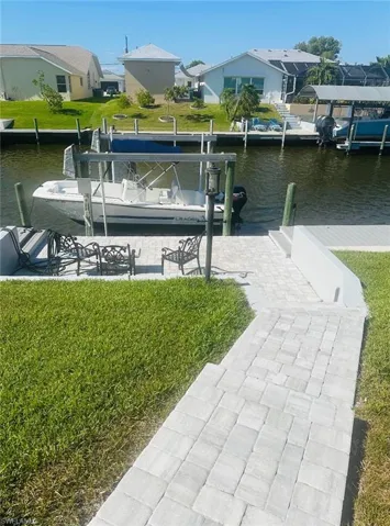 Dock area with boat lift, a water view, and a yard