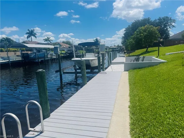 Dock area featuring boat lift, a lawn, and a water view