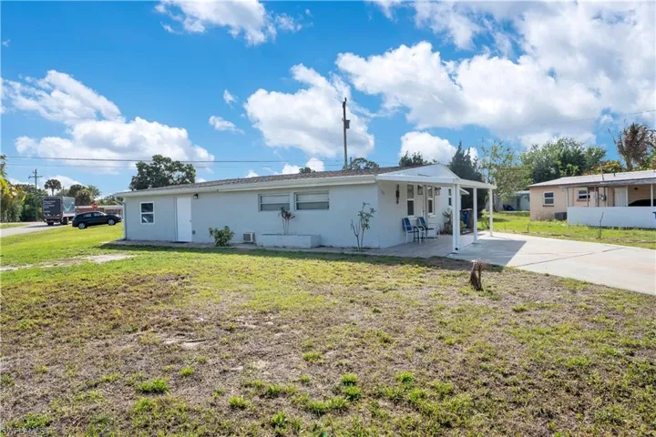Ranch-style house featuring a front yard, stucco siding, a patio area, driveway, and a carport
