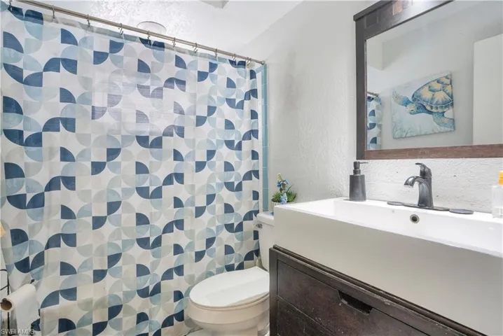 Bathroom with a textured wall, vanity, and a shower with curtain