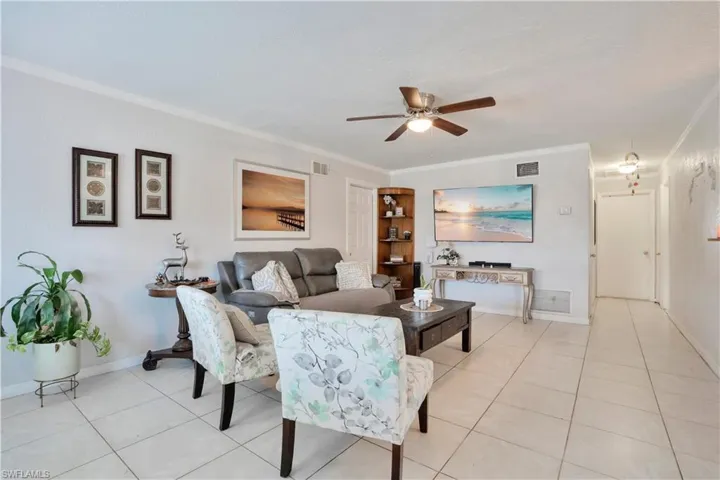 Living area featuring crown molding, ceiling fan, and light tile patterned flooring