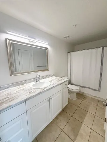 Bathroom featuring a vanity with white cabinetry, a stone-finish countertop, and an integrated sink with a chrome faucet