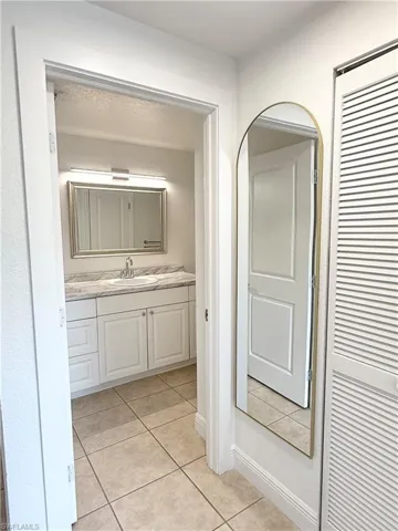 Bathroom featuring a single vanity with a light-toned countertop, a rectangular mirror, and a wall-mounted light fixture
