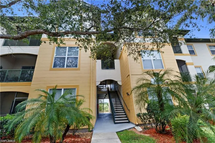 Multi-story building exterior featuring a light yellow facade with white trim