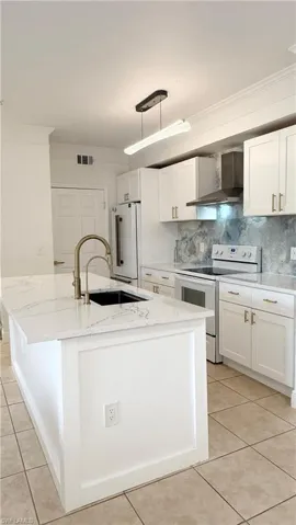 Kitchen featuring a large island with a black sink, a brushed brass faucet, and white countertops