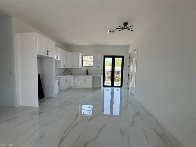 Kitchen featuring marble finish floor, visible vents, white cabinetry, a sink, and baseboards