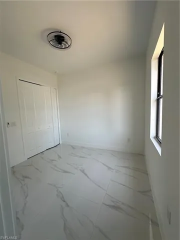 Unfurnished bedroom featuring marble finish floor, baseboards, and a closet