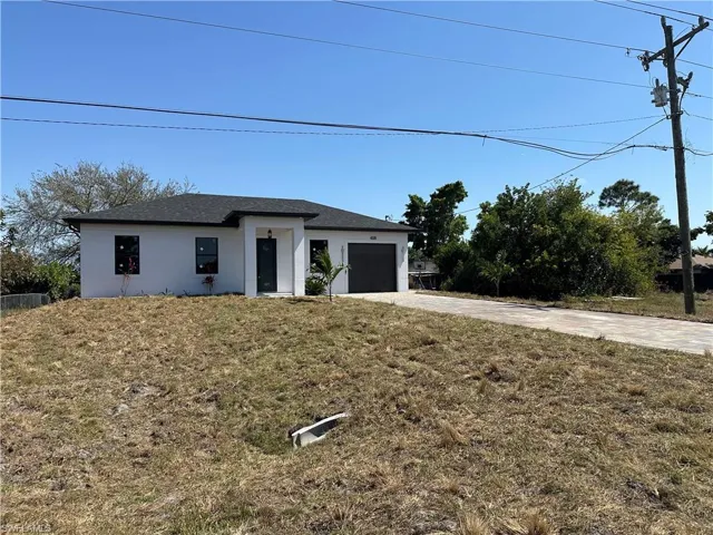 View of front of property with driveway, a front lawn, an attached garage, and stucco siding