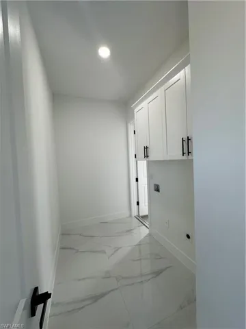 Clothes washing area featuring hookup for a washing machine, marble finish floor, cabinet space, and baseboards